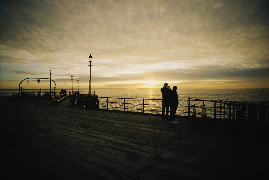 A couple watching the sunset on the pier