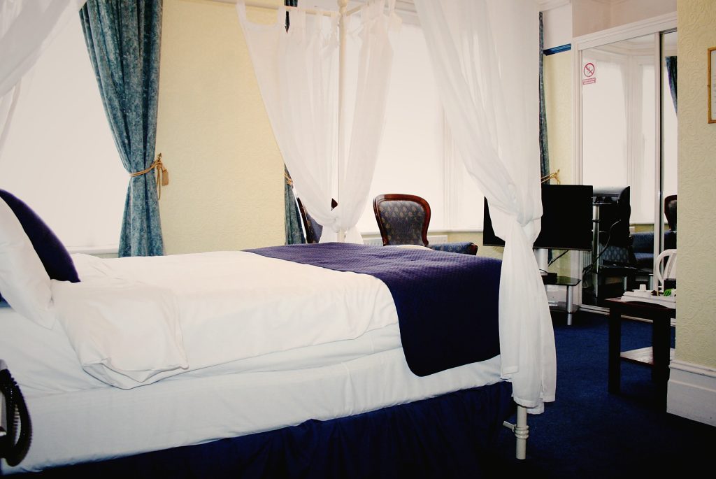 Four-poster style bedroom with navy throw