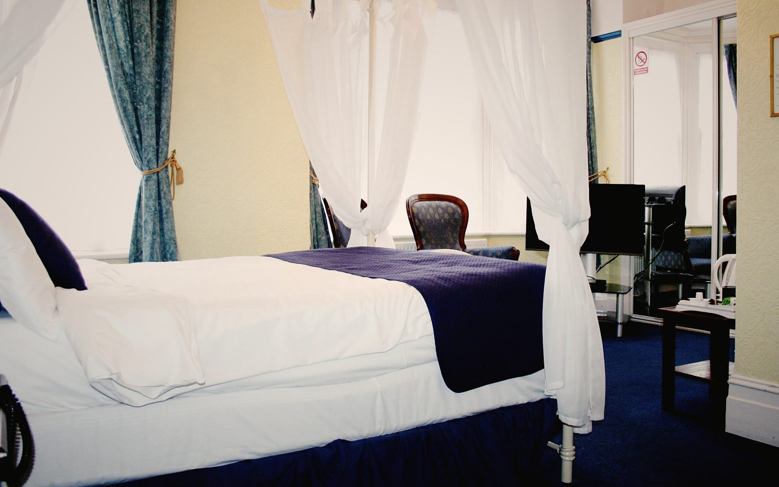 Four-poster style bedroom with navy throw
